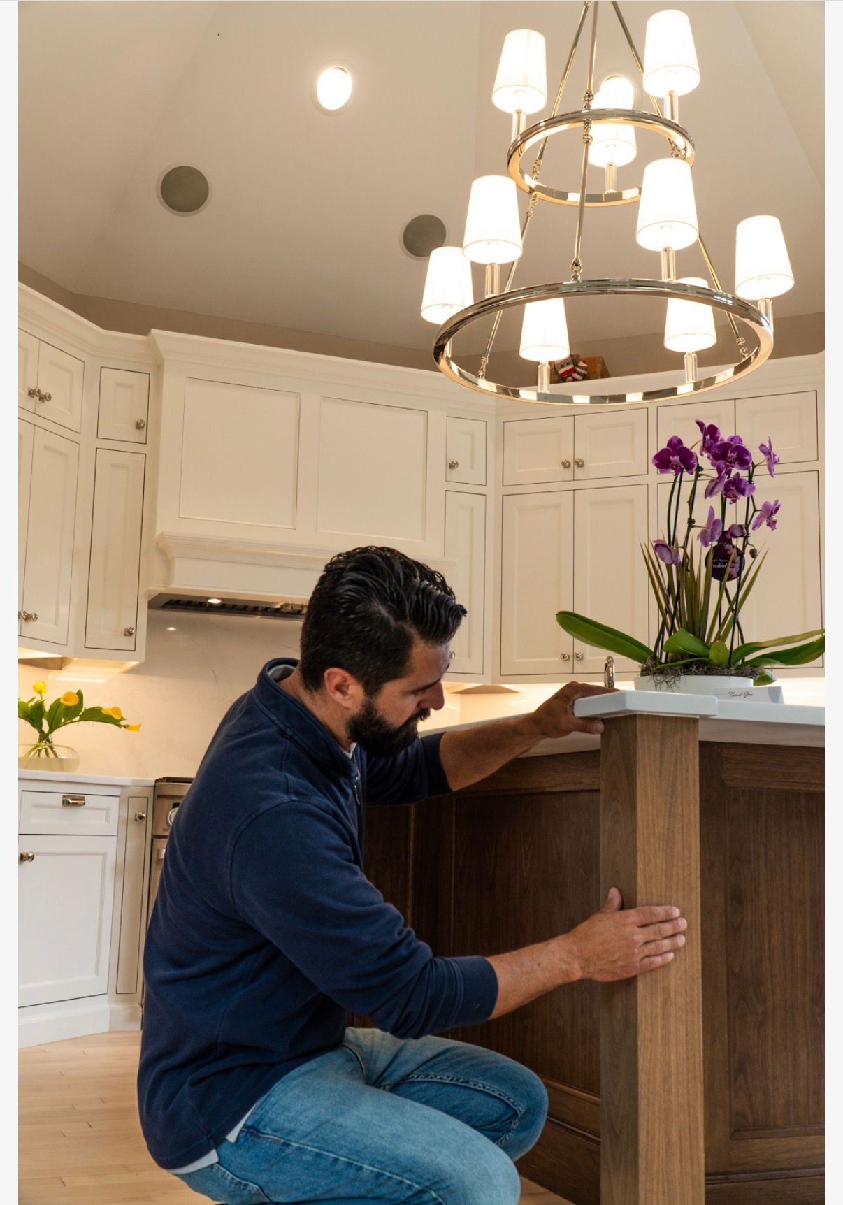 Craftsman fitting the walnut island in place under the chandelier