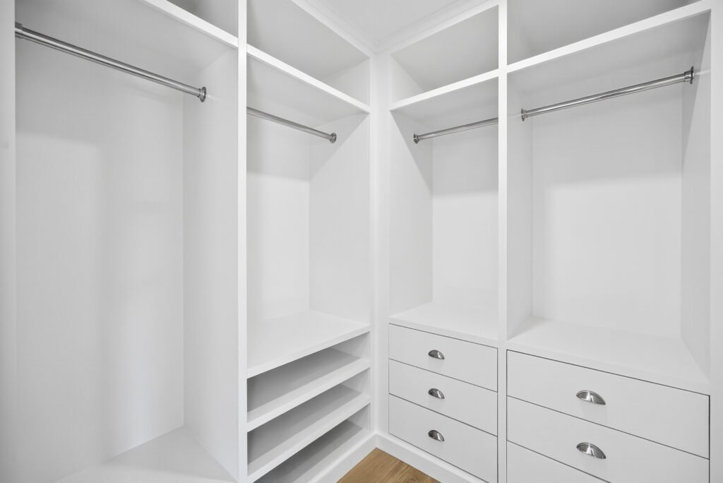 Custom white walk-in closet with hanging rails and drawers